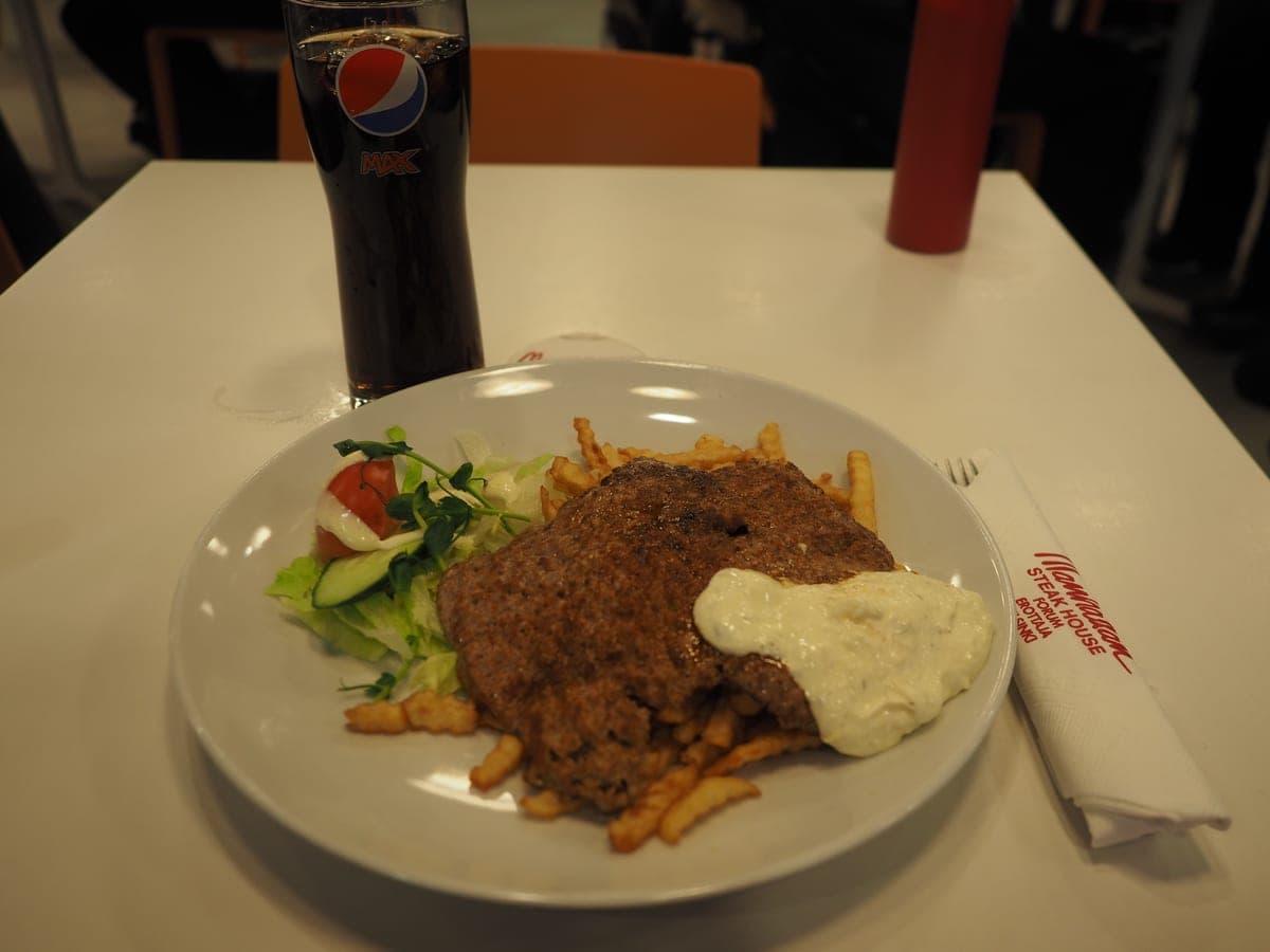 A plated steak with sides on a dark restaurant table.
