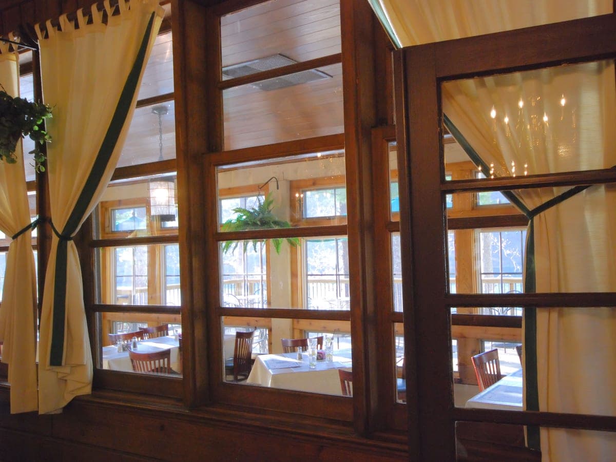 A restaurant porch deck overlooking a lake at dusk — rocking chairs, open water beyond.