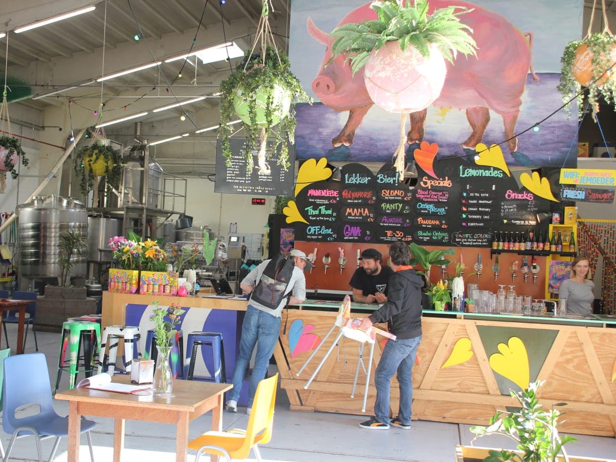 Interior of a craft brewery taproom — tap handles, exposed concrete, patrons at tables.